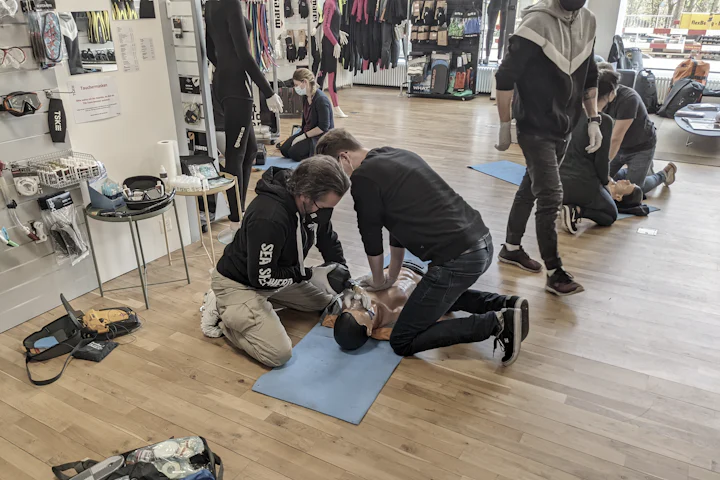 Plusieurs binômes travaillent en parallèle sur des mannequins posés au sol, lors d’une session collective.